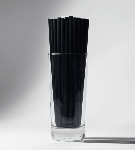 A group of 8-inch black compostable hemp straws in an empty glass